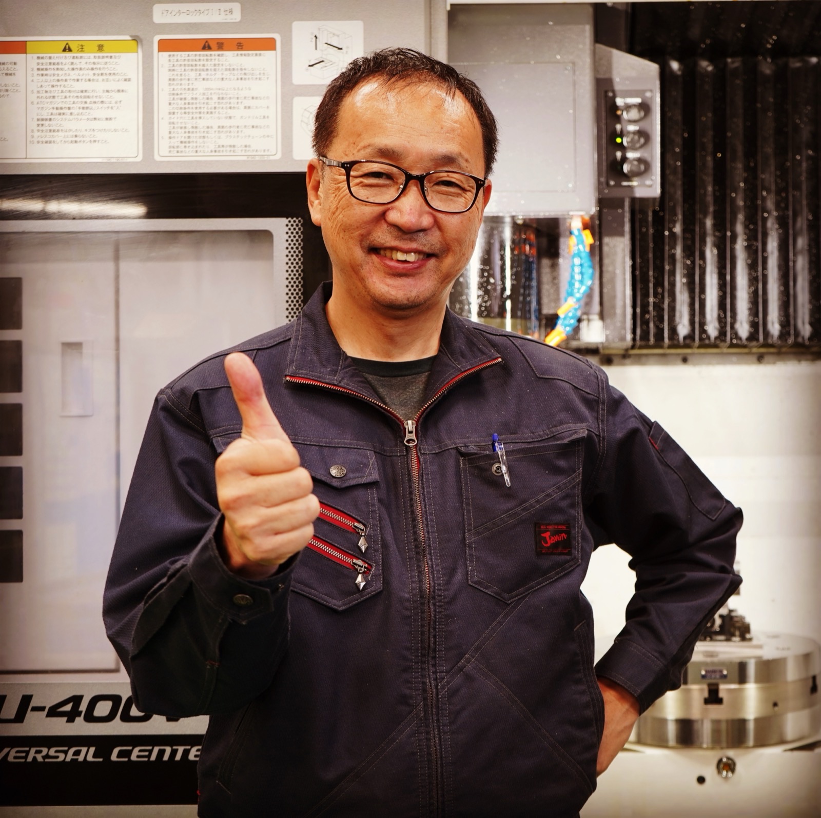 SAKAKI Gear founder Takashi Sakakibara giving a thumbs-up at the 5-axis machining center in Kasugai, Japan